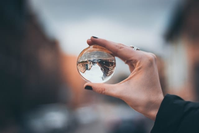 a hand holding a small transparent glass ball