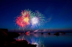 colorful fireworks exploding over a lake in the night sky