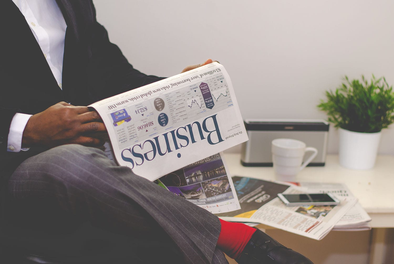 man sitting cross-legged reading the business section of a newspaper