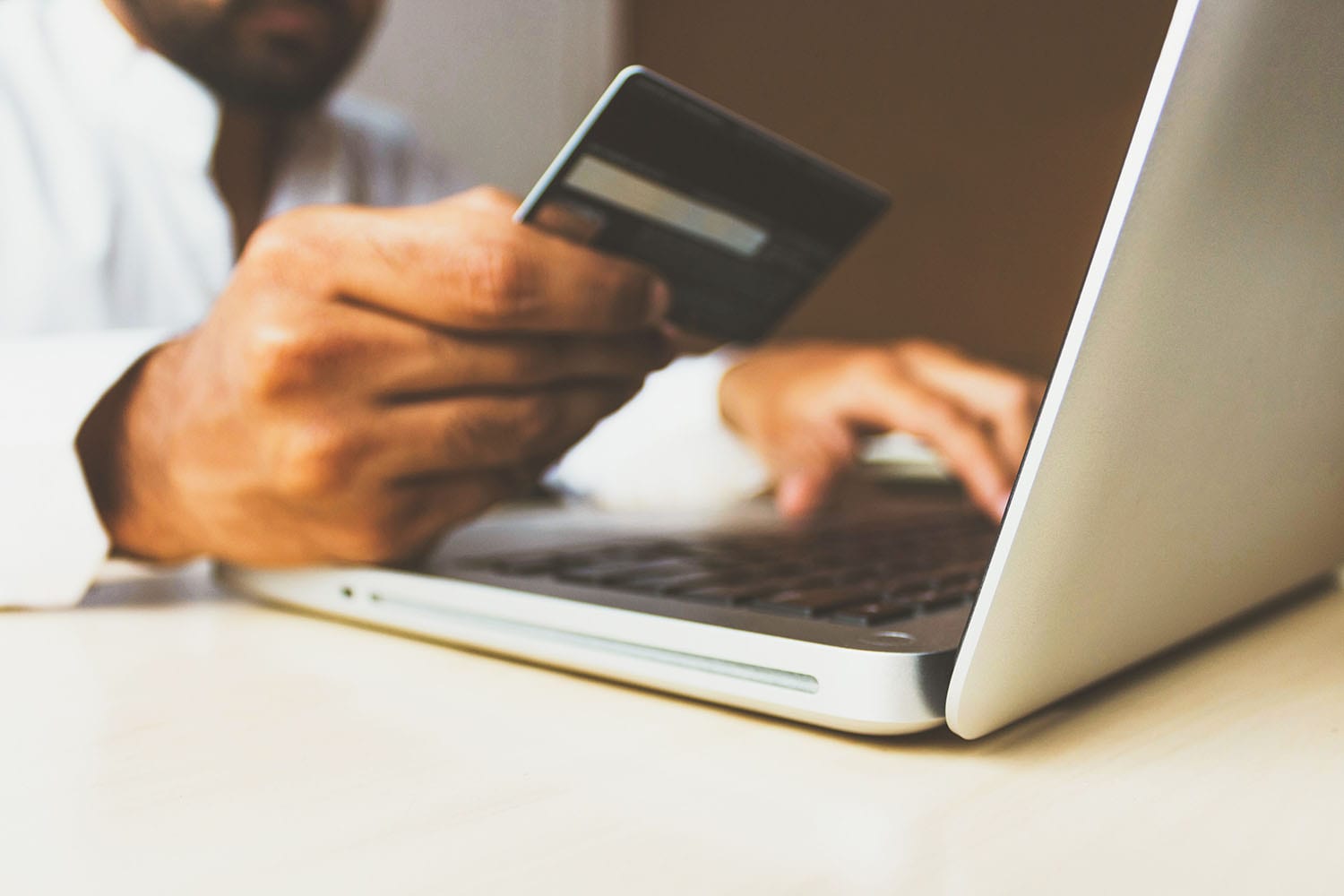 person looking at a credit card while typing information into a laptop