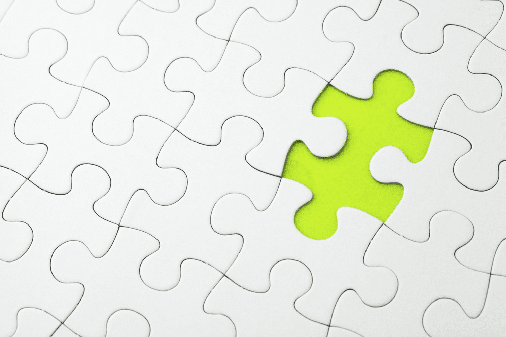 white jigsaw puzzle with one missing piece uncovering neon green underneath