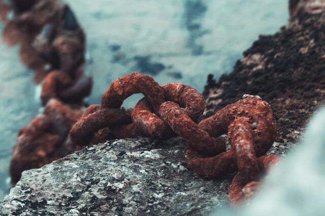 large brown corroded metal chain sitting on top of another gray metal