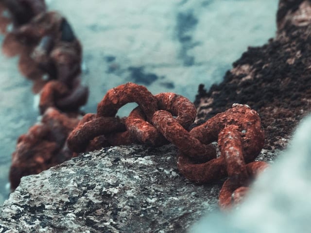 large brown corroded metal chain sitting on top of another gray metal