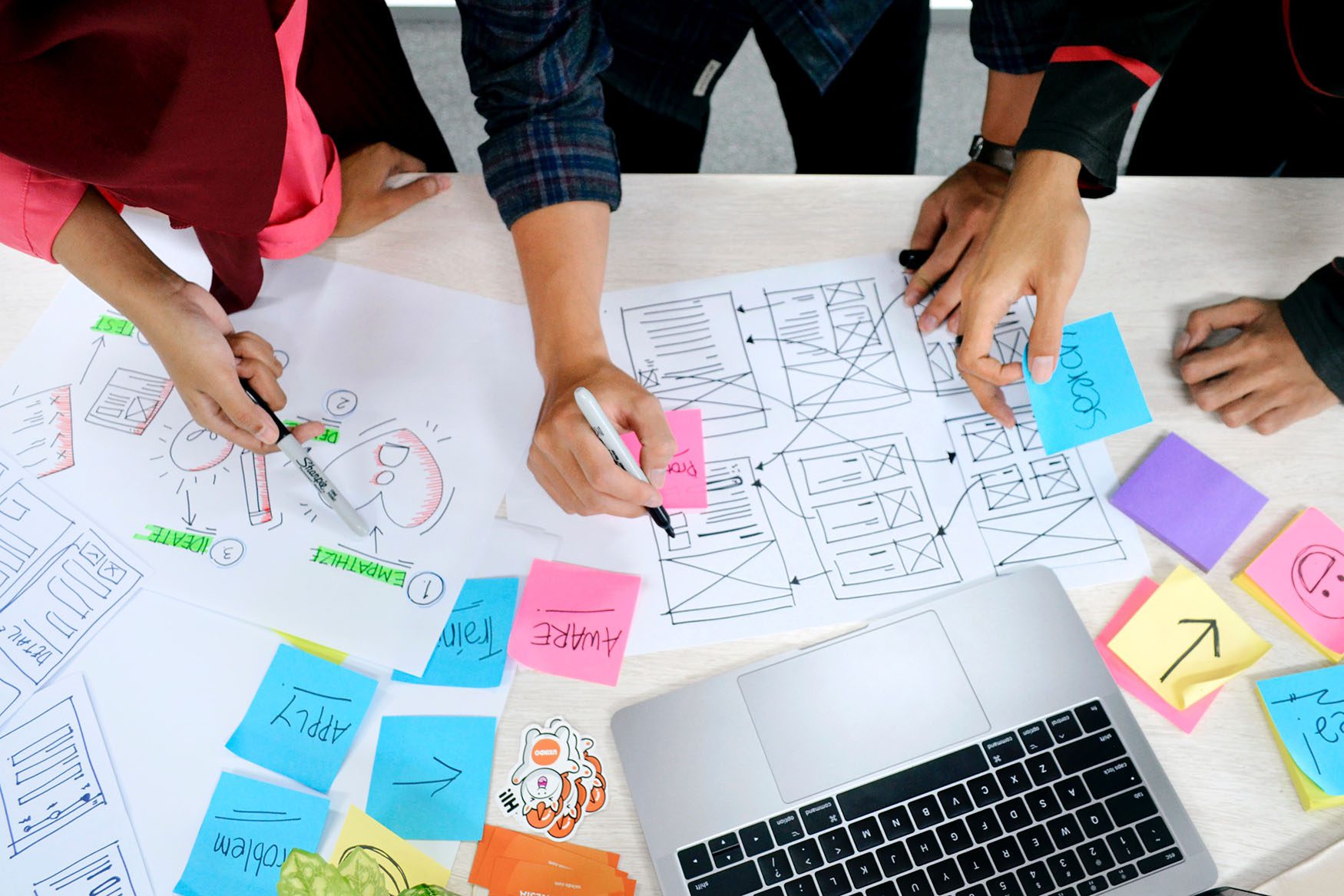 people gathered around a table of documents and technologies writing notes and collaborating