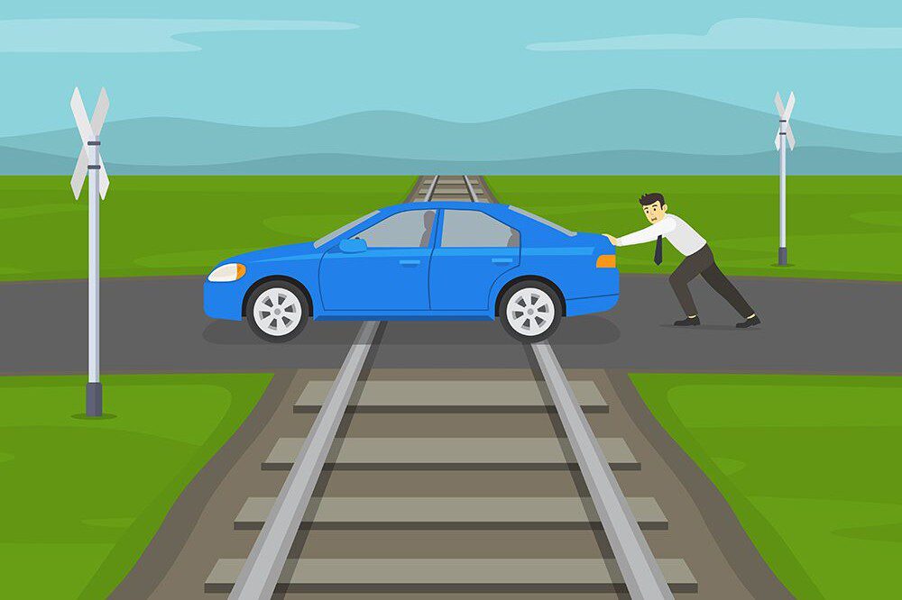 cartoon image of a person pushing a blue car across a railroad track