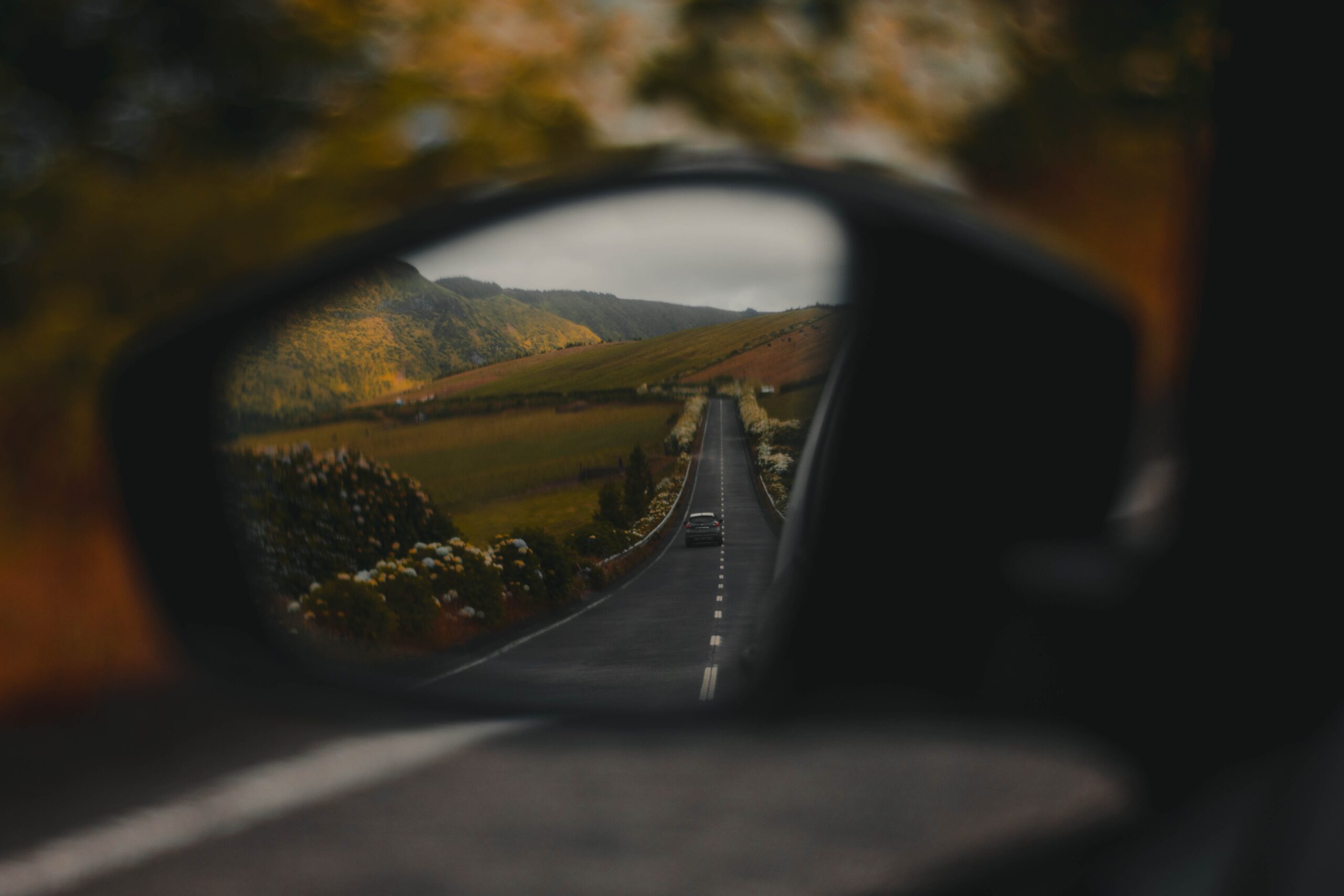 view from a side mirror on a car driving down a winding country road