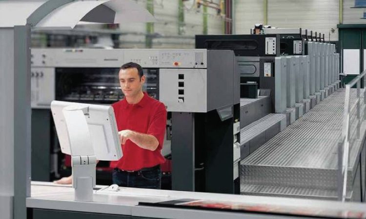 man in red shirt at a control panel in a manufacturing facility