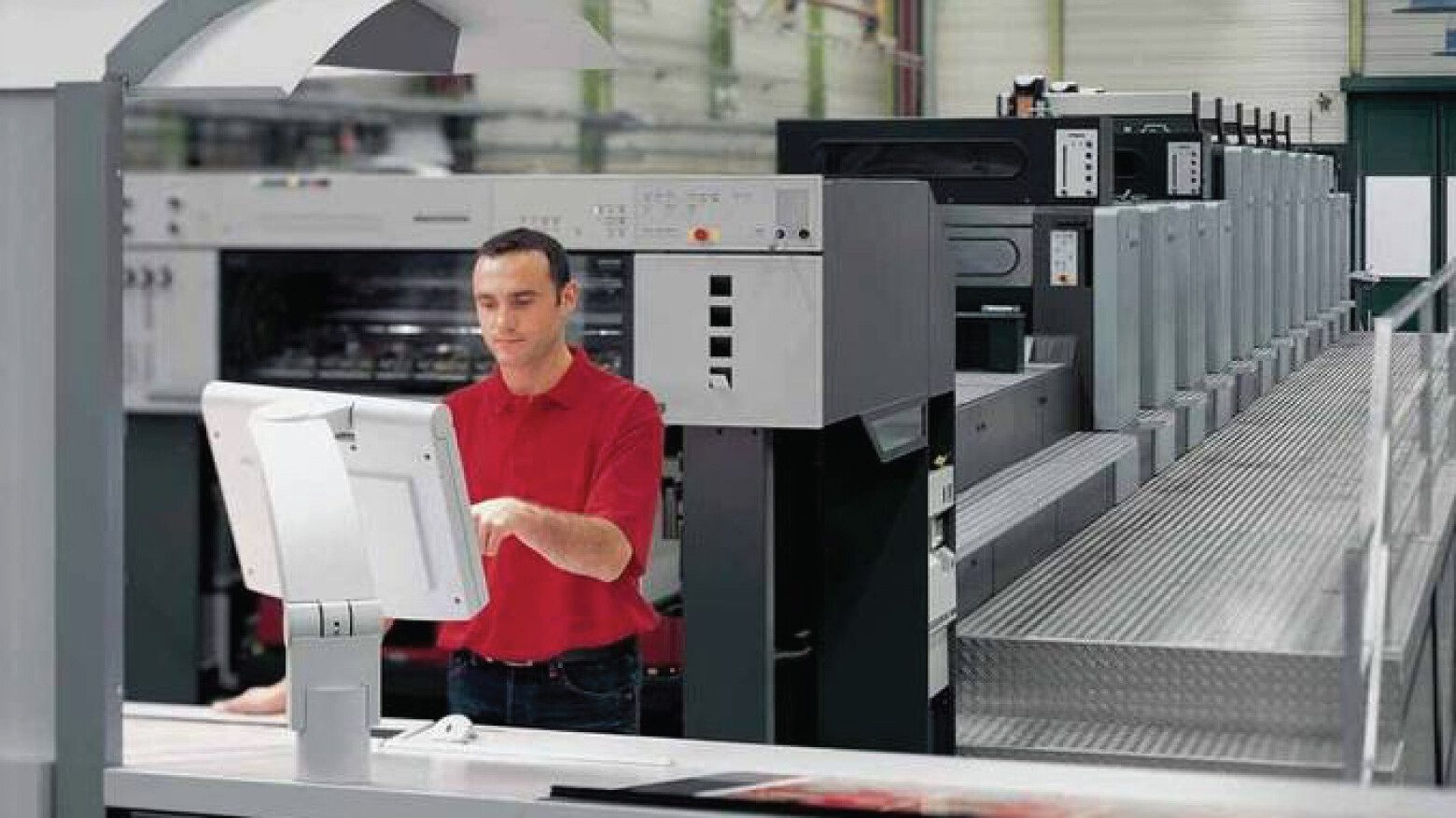 Man in red shirt at a control panel in a manufacturing facility