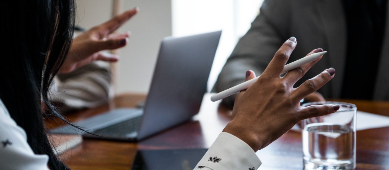 close up of hands and a laptop computer sitting at a desk with a glass of water