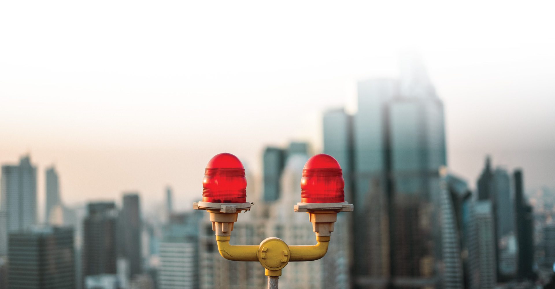 two signaling lamps with a cityscape in the distant background